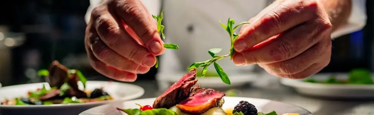 Kokk seab restoraniköögis rooga taldrikule